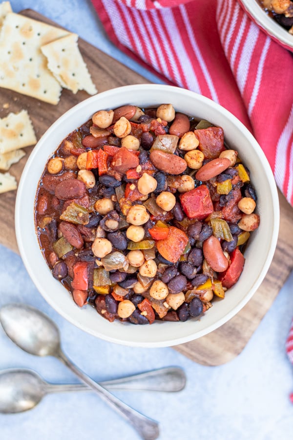 A white bowl for slow cooker vegetarian chili without any garsnishes showing of a lot of beans and colorful vegetables.