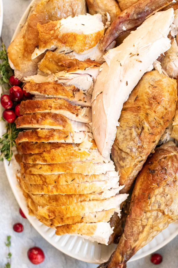 Close up of sliced turkey breast showing golden brown skin and a moist looking piece of turkey tender meat.