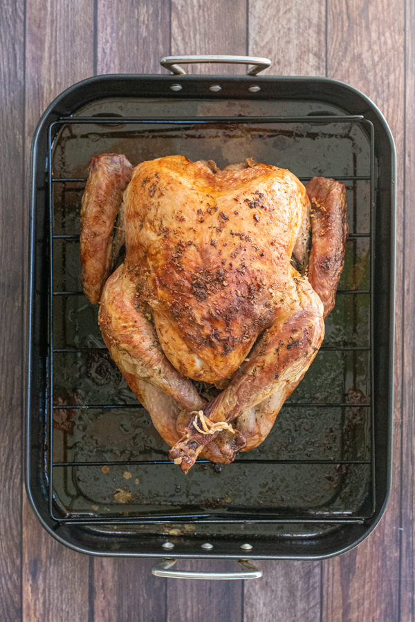 Overhead of a dry brine turkey on a roasting pan just pulled out of the oven.