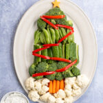 Pinterest Pin with text overlay Christmas Tree Veggie Tray. Image of a platter with vegetables shaped into a Christmas tree with decorations.