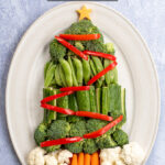 Pinterest Pin with text overlay Christmas Tree Veggie Tray. Image of a platter with vegetables shaped into a Christmas tree with decorations.
