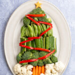 Pinterest Pin with text overlay Christmas Tree Veggie Tray. Image of a platter with vegetables shaped into a Christmas tree with decorations.