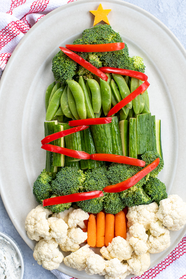 Close up of vegetables shaped like a Christmas tree complete with red vegetables as decorations.
