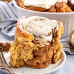 Pinterest Pin with text overlay 'Gingerbread Cinnamon Rolls'. Image of cinnamon roll on a plate with the outside ripped open revealing the inside.