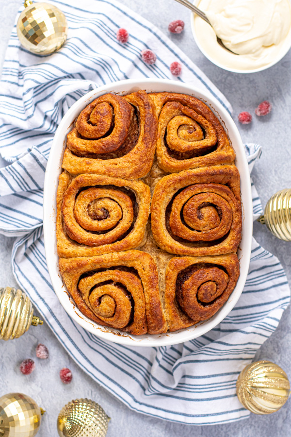 Unfrosted freshly baking gingerbread cinnamon rolls in a baking dish set on a blue kitchen towel.