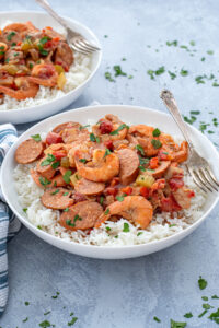 A large white bowl with a large scoop of gumbo on top of a bed of white rice with a fork.