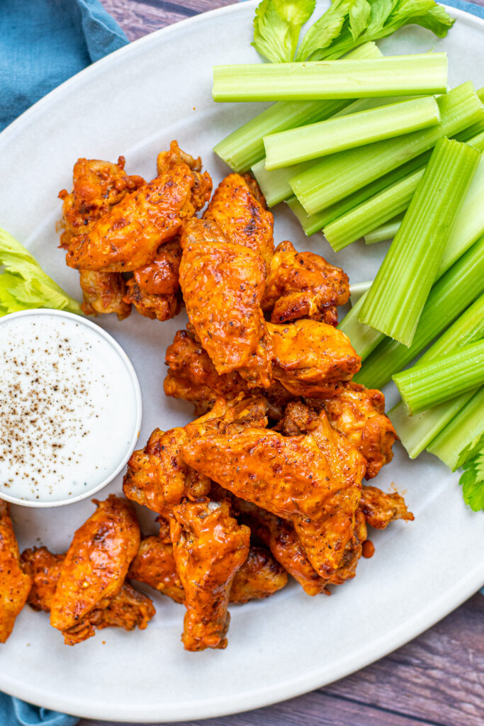 A large pile of chicken wings on a platter showing off sauces exteriors.