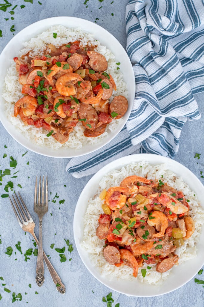 Flatly looking down at two large bowls of rice topped with saucy shrimp gumbo.