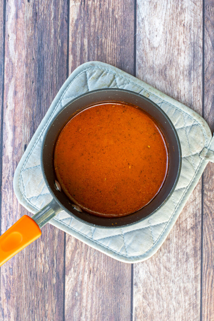 A small sauce pan holding the homemade hot wing sauce.
