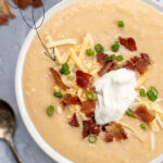 Pinterest Pin for with text overlay 'Baked Potato Soup in the Instant Pot'. Image of bowl of garnished baked potato soup.