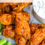 Pinterest Pin with text overlay 'Instant Pot Hot Wings'. Image of platter with pile of saucy chicken wings next to dipping sauce.