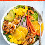 Pinterest Pin with text overlay 'Shrimp Salad with Avocado, Mano, and an Orange Vinaigrette'. Image of large bowl filled with mixed greens, grilled shrimp, avocado, and oranges.