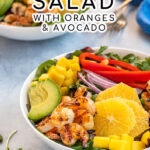 Pinterest Pin with text overlay 'Shrimp Salad with Oranges and Avocado'. Image of large bowl filled with mixed greens, grilled shrimp, avocado, and oranges.