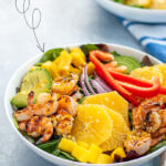 Pinterest Pin with text overlay 'Shrimp Salad with Orange Vinaigrette'. Image of large bowl filled with mixed greens, grilled shrimp, avocado, and oranges.