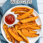 Pinterest Pin with text 'Baked Sweet Potato Wedges'. Image of plate with crispy sweet potato wedges and a little cup of ketchup.