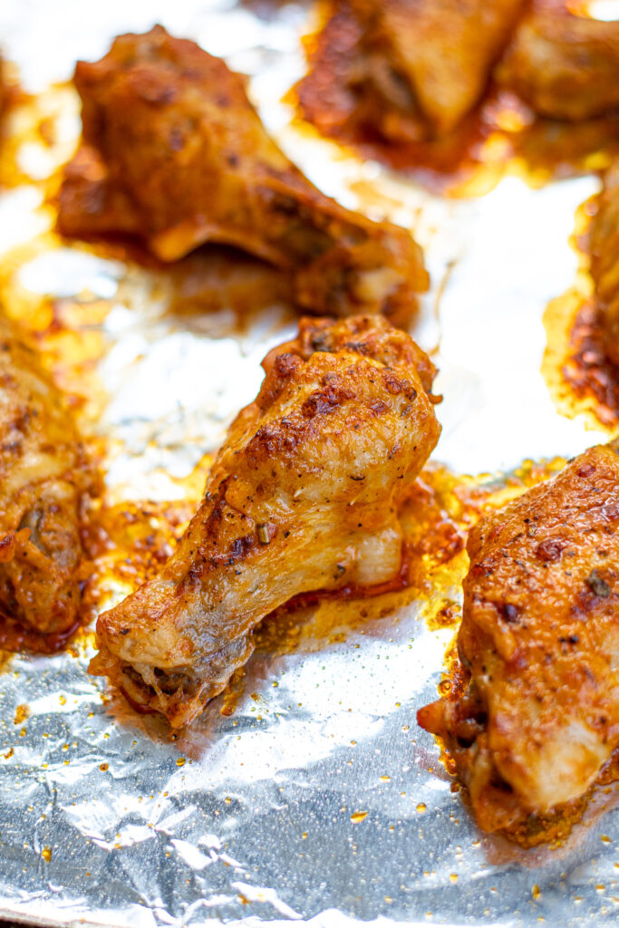Tray of crispy chicken wings fresh out of the oven showing a close up of a chicken drummie.