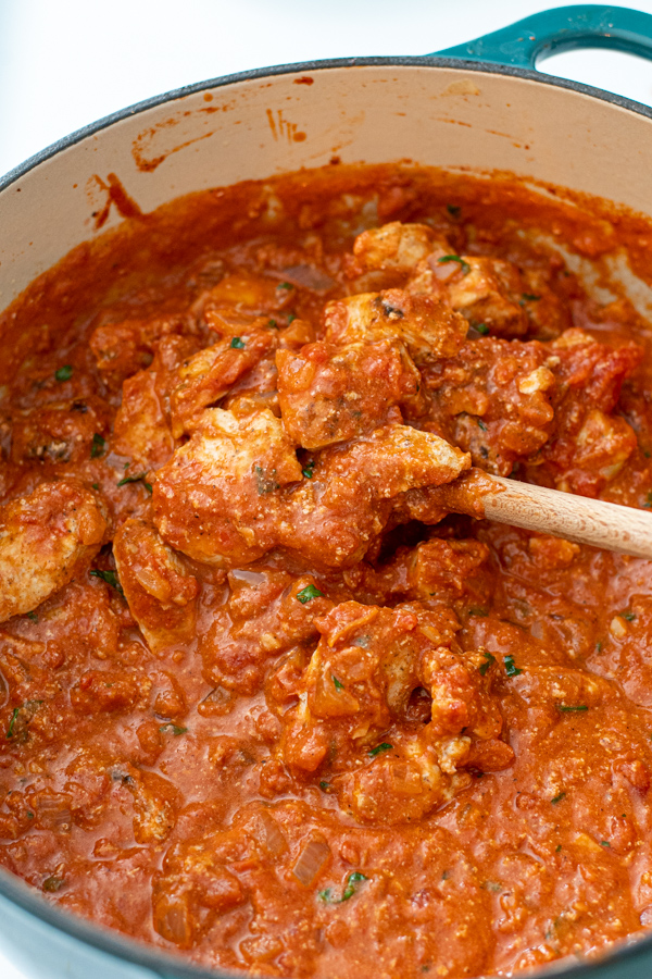Chicken added to tikka masala sauce in a large dutch oven.