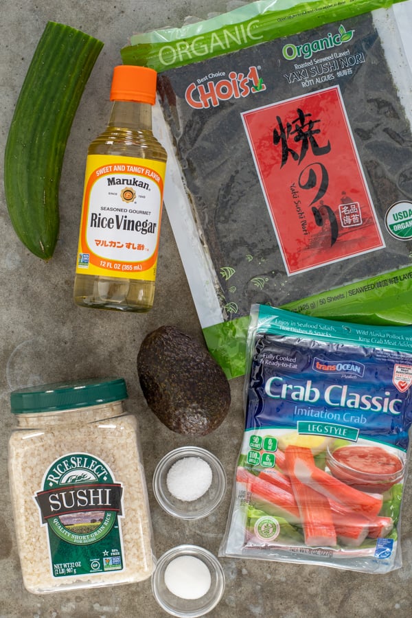 All the ingredients needed to make California roll Sushi sitting on a counter top.