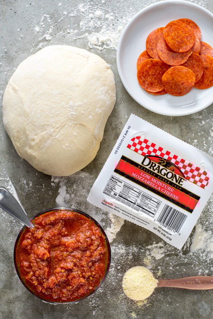 Ingredients laid out for making homemade pizza on a countertop.