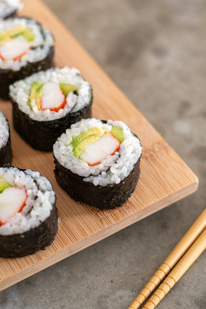 Platter of California rolls next to chopsticks.