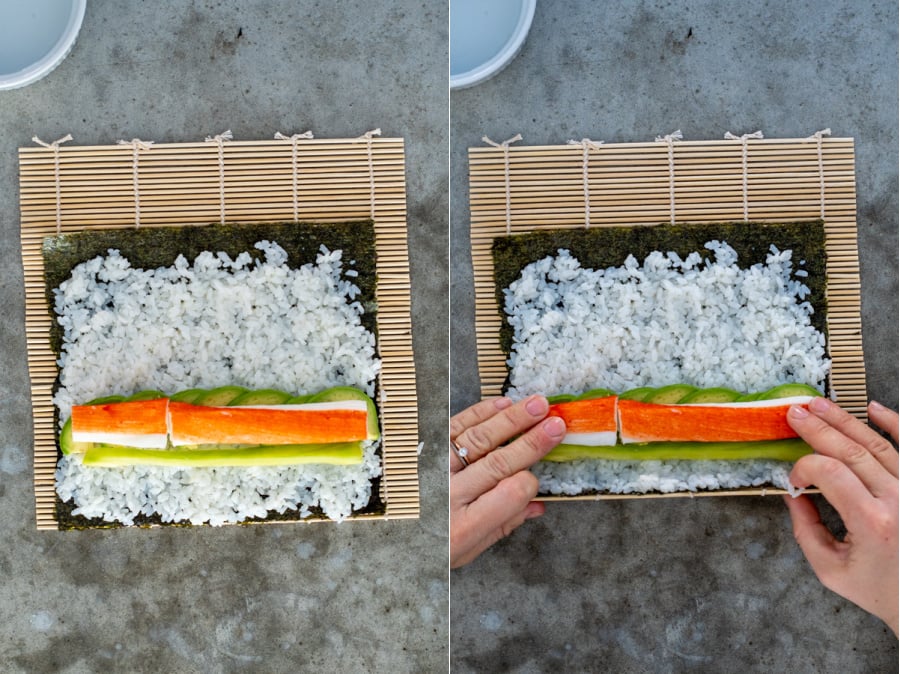 Step four of a California roll adding the crab and grabbing the end of the mat to prepare for rolling.