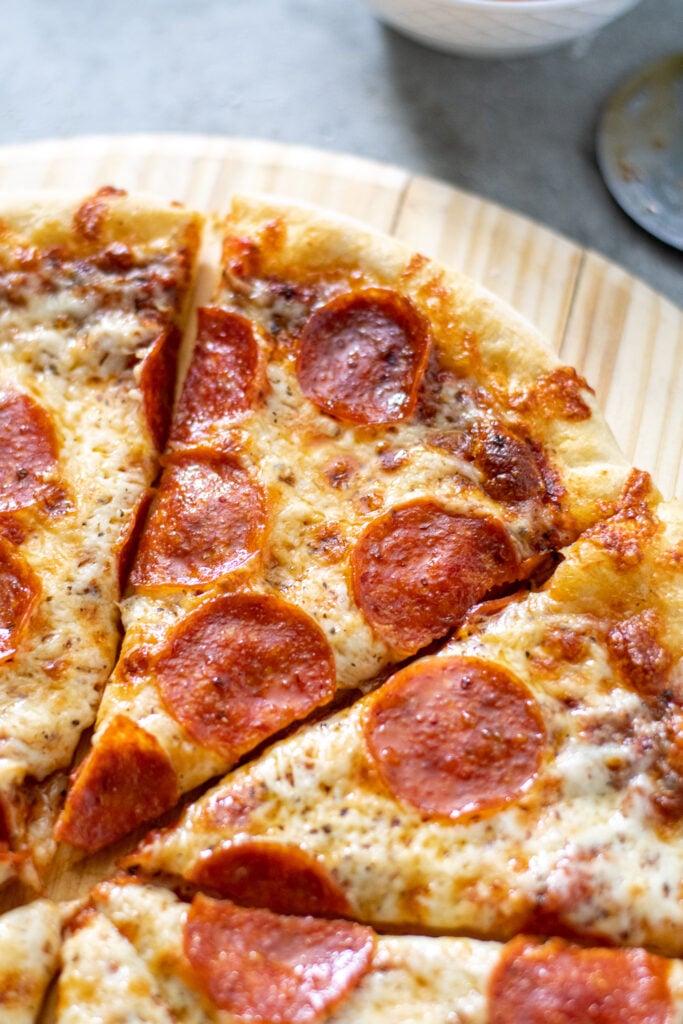 Close up of a slice of homemade pepperoni pizza showing of golden cheese.