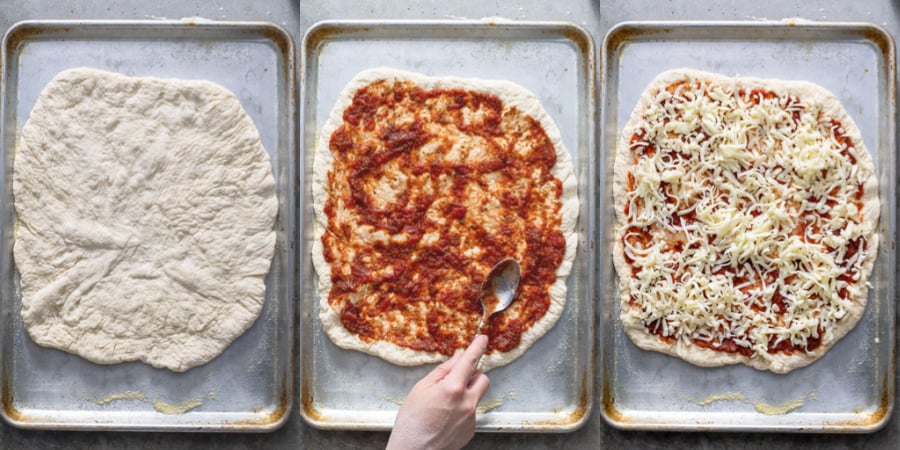 A pizza on a sheet pan being topped with sauce and cheese.