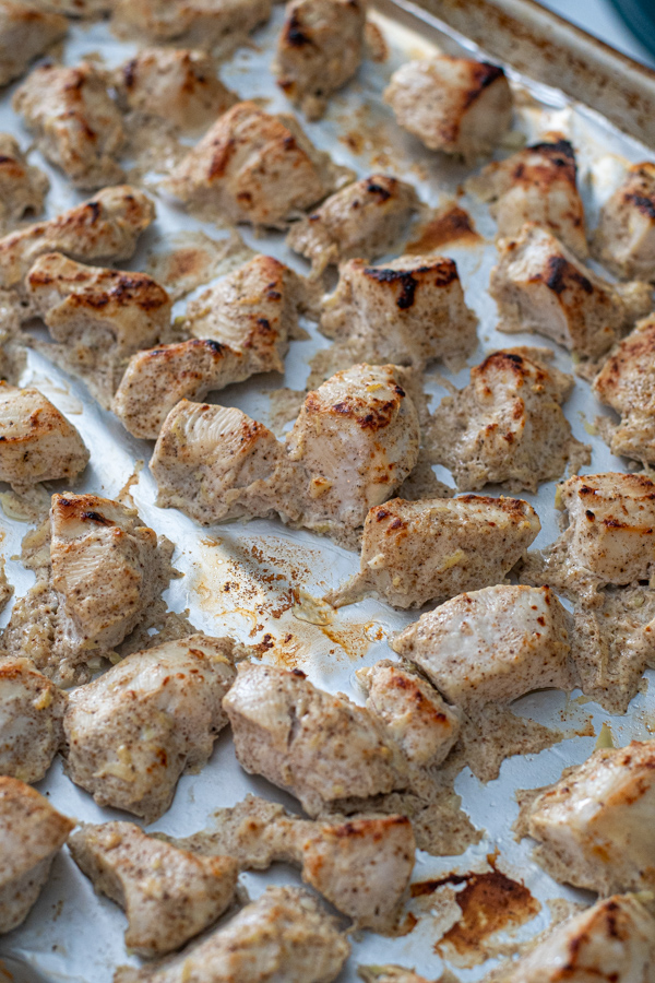 Freshly broiled chicken on a sheet pan ready to be added to tikka masala sauce.