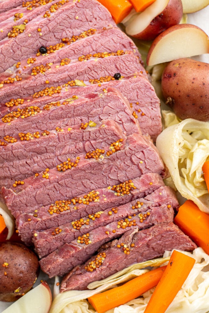 Close up of the cooked corned beef in slices topped with whole grain mustard.