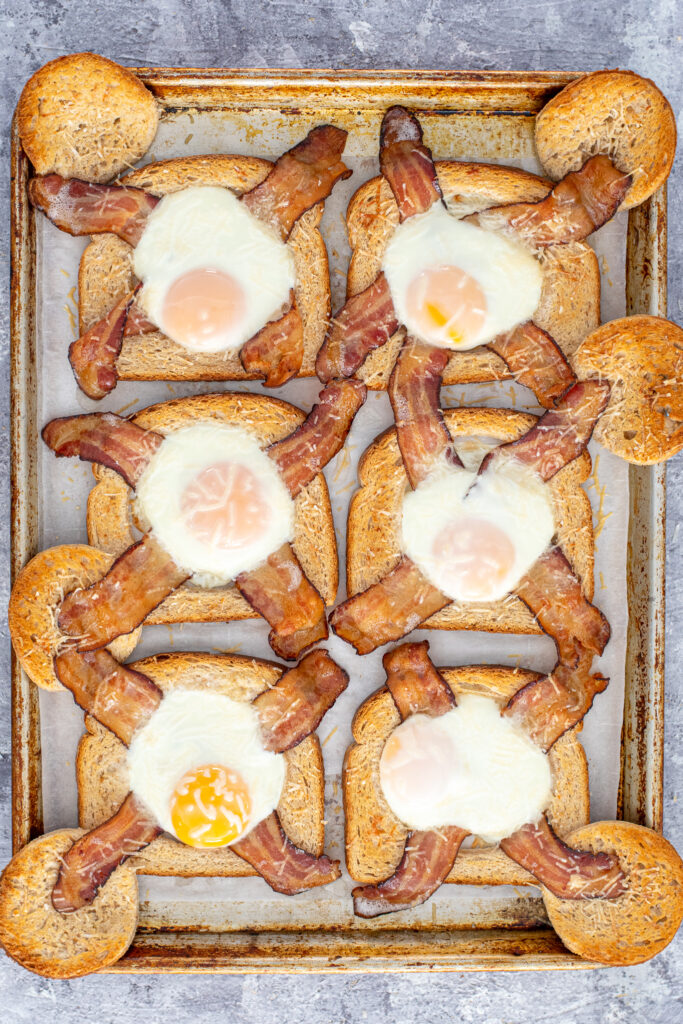 Cooked sheet pan egg in a hole fresh out of the even with golden toast and set eggs.