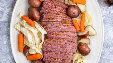 A platter filled with Guinness Corned Beef and Cabbage with carrots and potatoes.