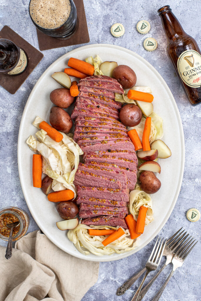 A platter filled with Guinness Corned Beef and Cabbage with carrots and potatoes.