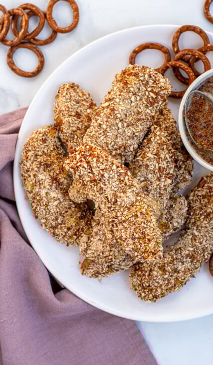 Plate full of a stack of Pretzel Crusted Chicken Tenders next to a small bowl of honey mustard.