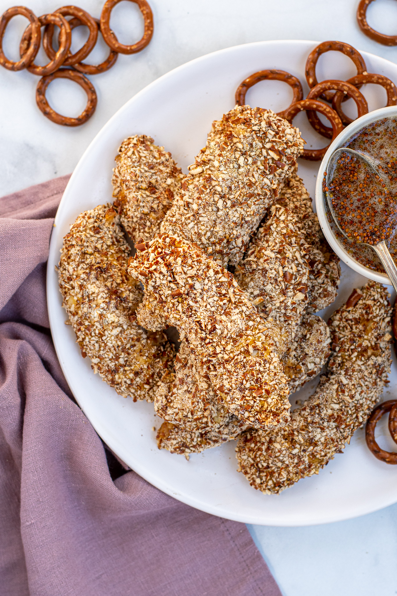 Plate full of a stack of Pretzel Crusted Chicken Tenders next to a small bowl of honey mustard.