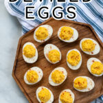Pinterest Pin with text 'Simple & Easy Deviled Eggs', image of many deviled eggs laid out on a wood plater garnished with red paprika.