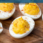 Pinterest Pin with text 'Simple & Easy Deviled Eggs', image of close up of a deviled egg laid out on a wood plater garnished with red paprika.