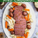 Pinterest Pin with text ' Slow Cooker Guinness Corned Beef and Cabbage', Image of platter with slices of corned beef and vegetables.