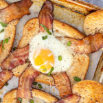 Pinterest Pin with text overlay 'Sheet Pan Egg in a Hole', image of a sheet pan with a close shot of a baked egg in a hole toast with bacon.