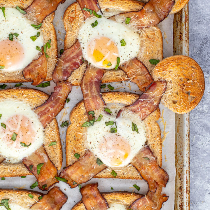 Zoomed in view of two egg in a hole toasted on a sheet pan sitting next to the toasted center circles.