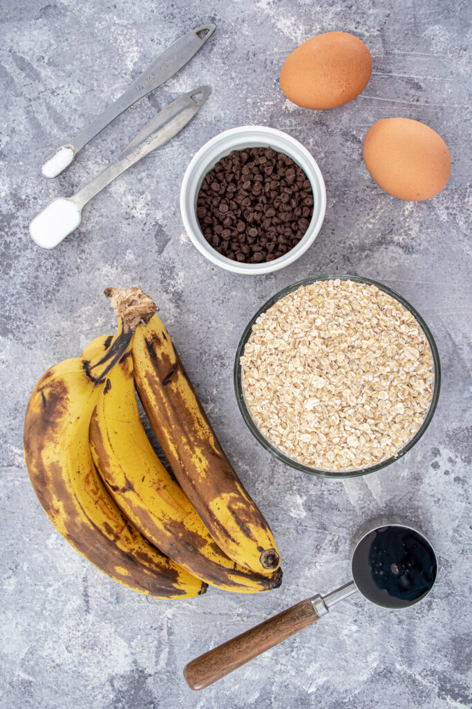 Ingredients for flourless banana muffins showing off bananas, oats, eggs, and mini chocolate chips as a few of the ingredients.