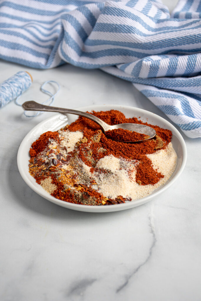 Spices used to make fajita seasoning messily spread across a plate with a spoon.