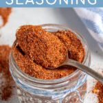 Pinterest Pin with text 'Fajita Seasoning', image of a jar of spices with a spoon resting full of fajita seasoning.