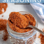 Pinterest Pin with text 'Fajita Seasoning', image of a jar of spices with a spoon resting full of fajita seasoning.