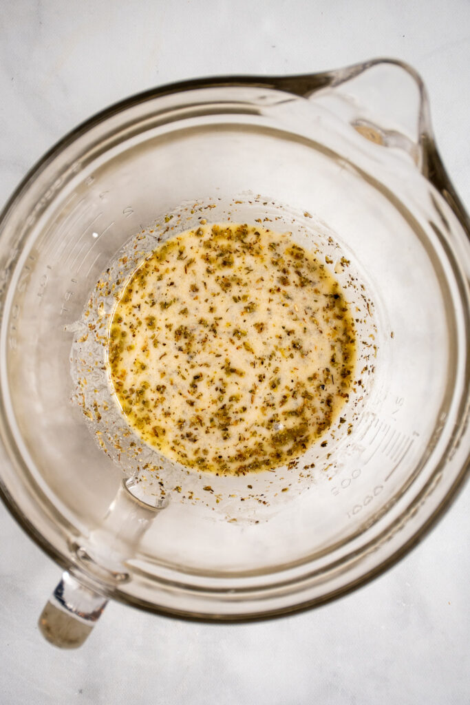 Glass bowl with a quick greek marinade with yogurt, vinegar, and spices.