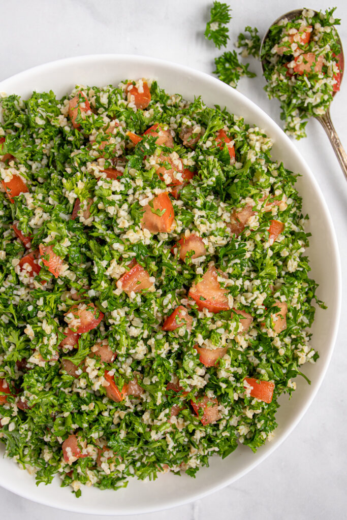 Close up view of tabbouleh salad recipe in a bowl showing off parsley, tomatoes, and bulgur.