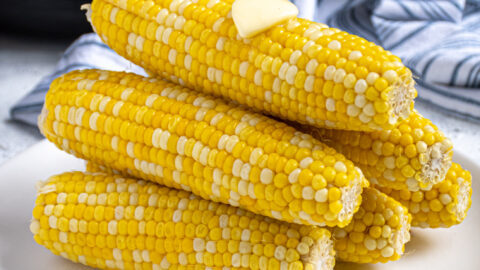 Pyramid shaped stack of freshly cooked instant pot corn on the cob showing off bright yellow kernels complete with a slab of melted butter on top.