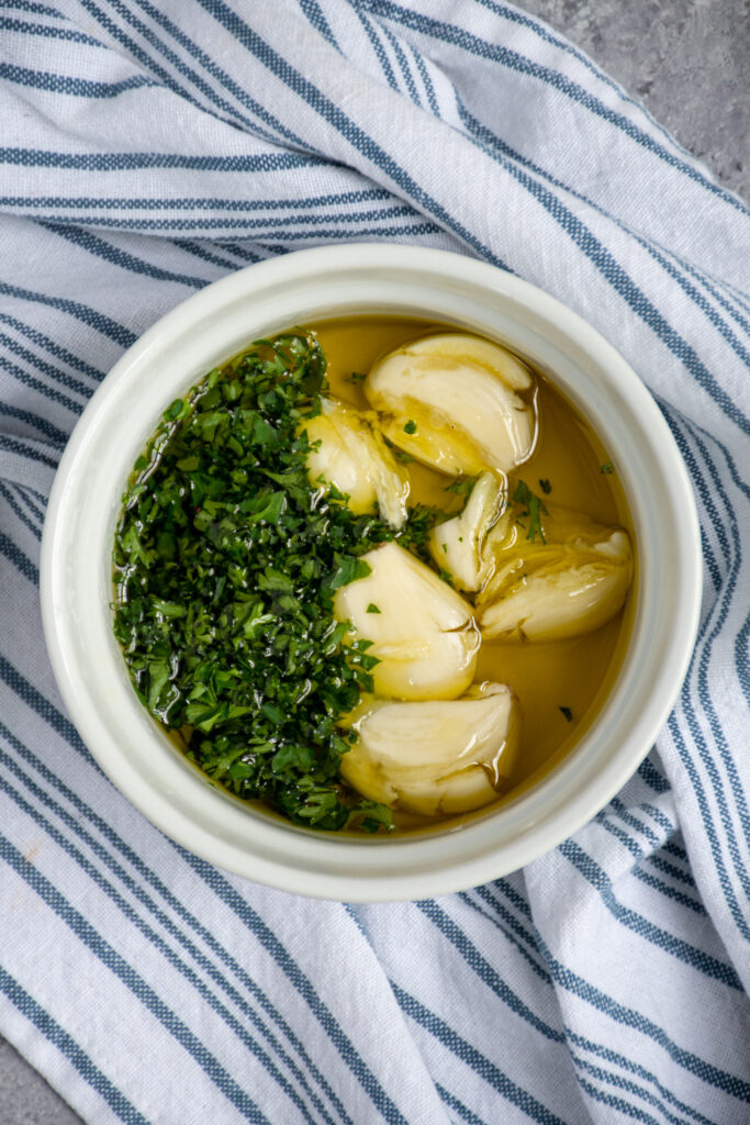 Small bowl with smashed garlic and chopped parsley infusing in olive oil.