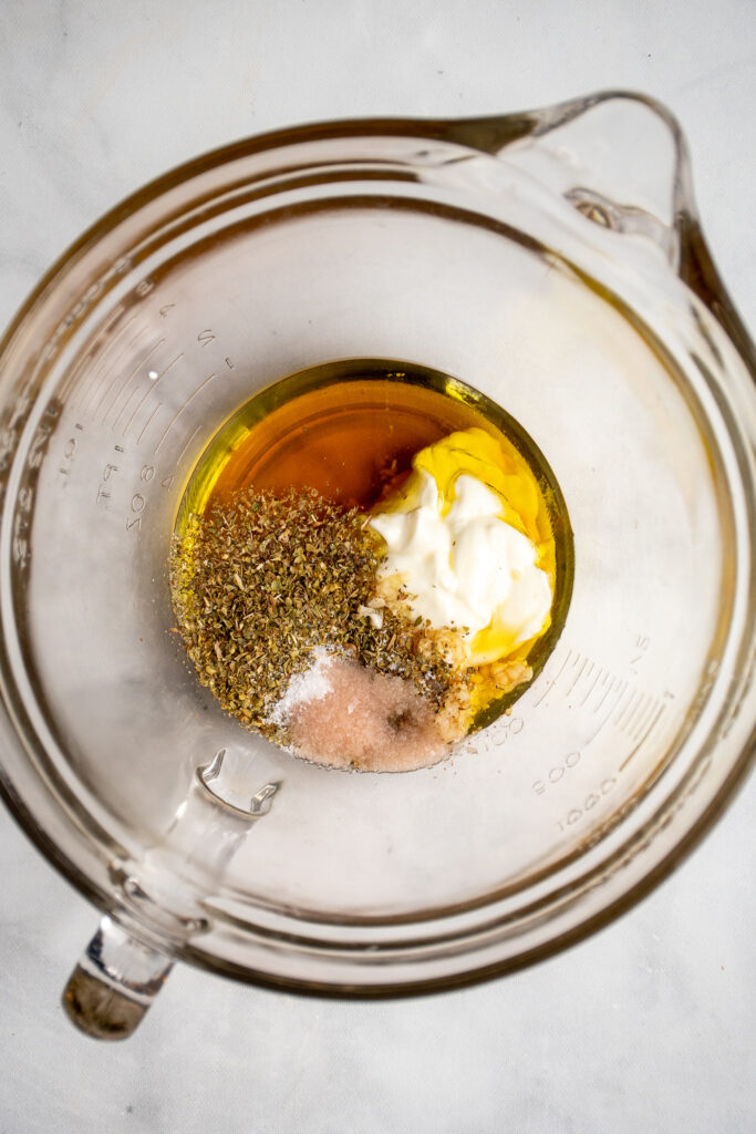 The ingredients for chicken greek marinade in a large glass bowl.