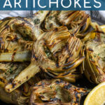 Pinterest Pin with text 'Grilled Artichokes', image of a close up of half an artichoke with perfect charred grill marks.