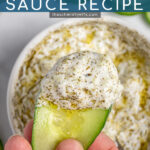 Pinterest Pin with text overlay 'Tzatziki Sauce Recipe', image of hand holding a cucumber with a large dip of tzatziki sauce on it.
